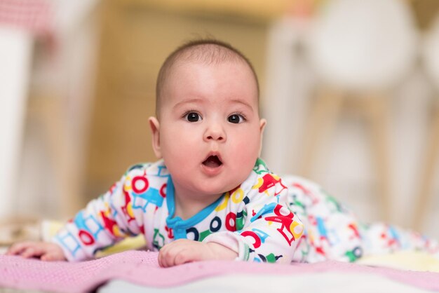 gelukkige mooie pasgeboren babyjongen liggend op kleurrijke dekens tijdens het spelen van de eerste spelletjes op de vloer thuis