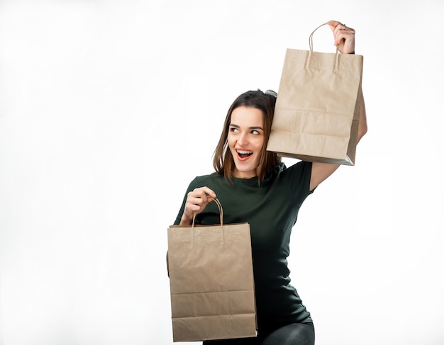 Gelukkige mooie vrouw die het winkelen zakken in elke hand opheft terwijl weg het kijken.