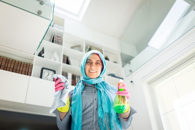 Gelukkige moslimvrouw die een modern huis schoonmaakt woonkamer foto van hoge kwaliteit