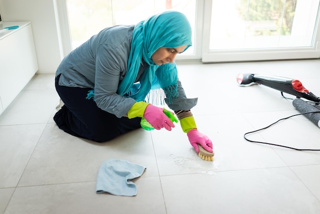Gelukkige moslimvrouw die moderne huiswoonkamer schoonmaakt van hoge kwaliteit foto