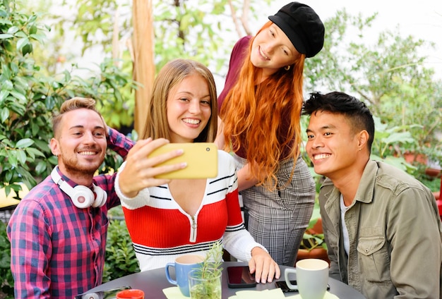 Gelukkige multi-etnische vrienden nemen selfie op mobiele telefoon in terras