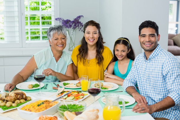 Gelukkige multigeneratiefamilie die maaltijd op lijst hebben thuis