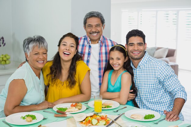 Gelukkige multigeneratiefamilie die maaltijd op lijst hebben thuis