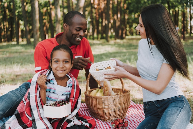 Gelukkige multinationale familie op picknick In het bos.