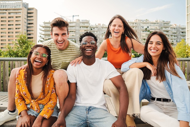 Gelukkige multiraciale jonge mensen die samen glimlachen en naar de camera kijken vijf tienervrienden die plezier hebben en lachen om buiten op straat Lifestyle Concept te fotograferen