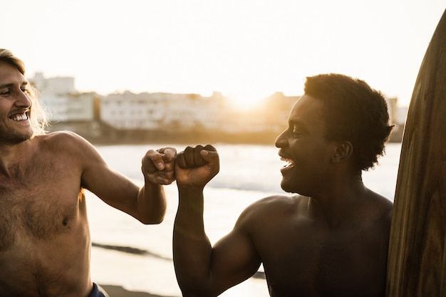 Gelukkige multiraciale surfers die plezier hebben op het strand na een surfsessie