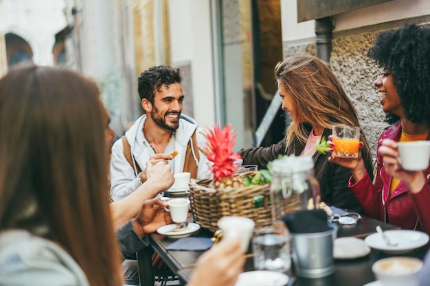 Gelukkige multiraciale vrienden eten en drinken buiten in vintage bar-restaurant Zachte focus op blond meisje hoofd