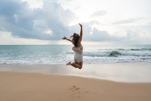 Gelukkige onbezorgde Aziatische vrouw die op het strand geniet. Zomer- en vakantieconcept. Kopieer ruimte