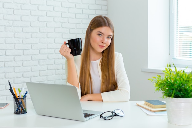 Gelukkige onderneemster die aan laptop op kantoor werkt