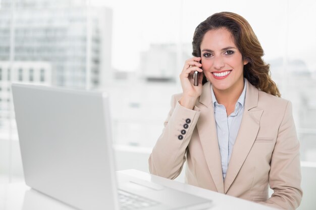 Gelukkige onderneemster op de telefoon bij haar bureau