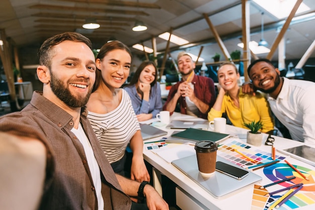 Gelukkige ontwerpers die selfie maken op de werkplek die aan een project werken