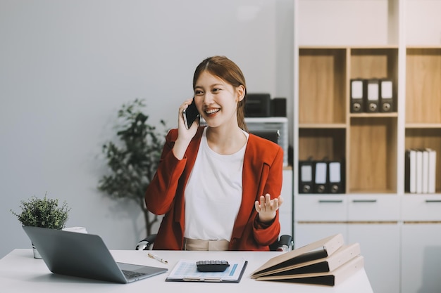Gelukkige opgewonden Aziatische zakenvrouw op kantoor die met een mobiele telefoon werkt.