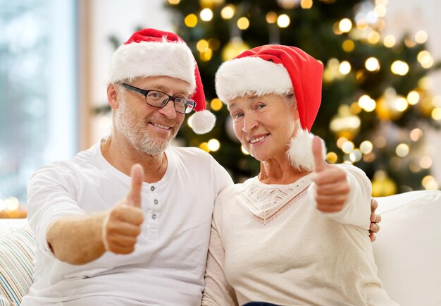 Gelukkige oudere echtpaar in kerstman helper hoeden thuis