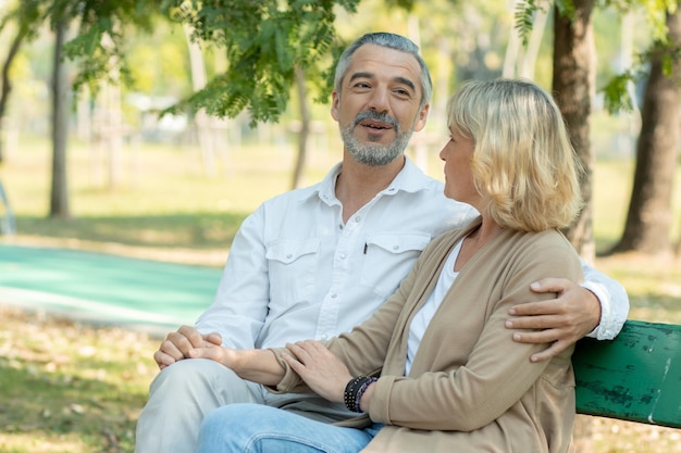 Gelukkige oudere liefdespaar groot en glimlachend in romantiek zitten in het park