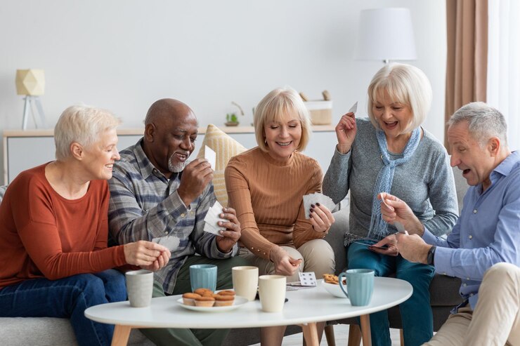 Gelukkige oudere vrienden die kaarten spelen terwijl ze thuis samen aan het chillen zijn