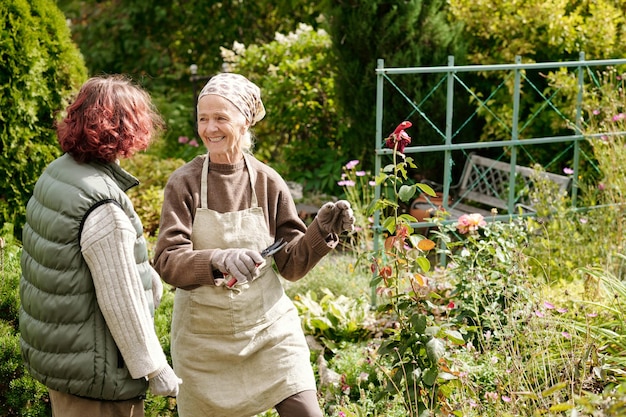 Foto gelukkige oudere vrouw die naar haar kleindochter kijkt terwijl ze allebei in de tuin werken