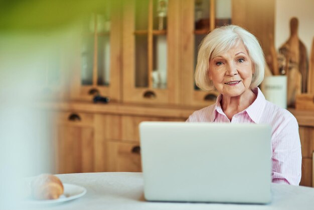 Gelukkige oudere vrouw die thuis computer gebruikt