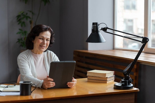 Gelukkige oudere vrouw van middelbare leeftijd die tablet vasthoudt, praat tijdens een videogesprek met familie van vrienden lachende volwassen oude senior grootmoeder die plezier heeft tijdens het praten met volwassen kinderen online