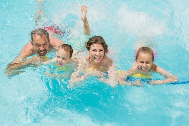 Gelukkige ouders en kinderen plezier in zwembad