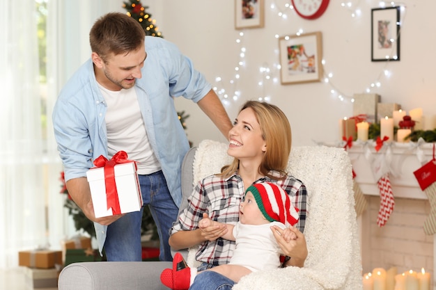 Gelukkige ouders met baby in versierde kamer voor Kerstmis