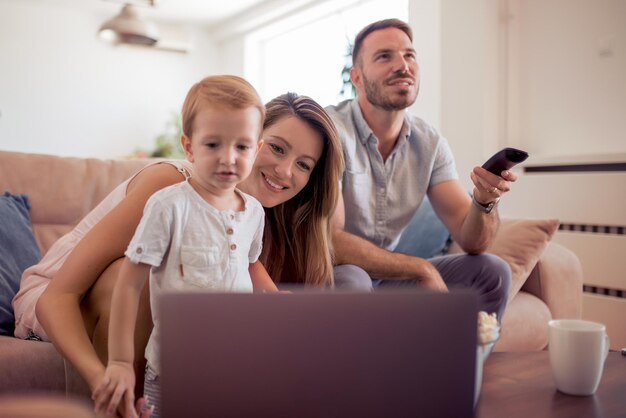 Foto gelukkige ouders met zoon die laptop in woonkamer gebruikt