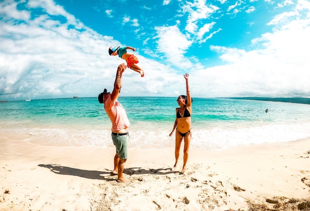 Gelukkige ouders spelen met hun zoon op een prachtig strand in australië.