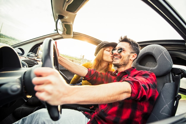 Gelukkige paar een converteerbare auto rijden bij zonsondergang op de weg