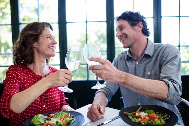 Gelukkige paar het roosteren champagnefluiten op middelbare leeftijd terwijl het hebben van lunch