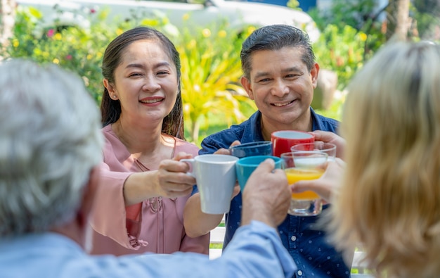 Gelukkige paar hogere clinking glazen met hun familie terwijl ontbijt samen thuis tuiniert