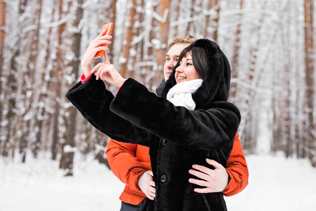 Gelukkige paar in de winter fotograferen van zichzelf met smartphone.