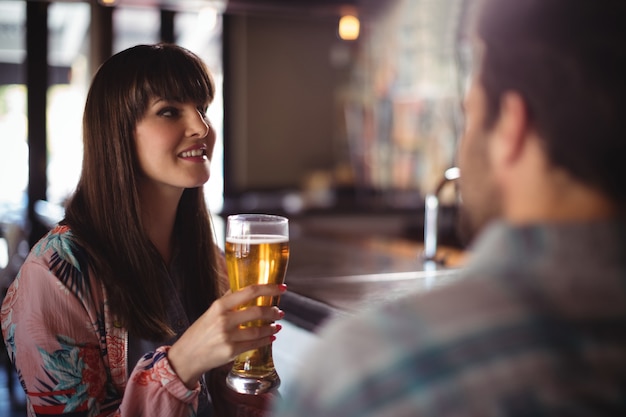 Gelukkige paar interactie terwijl het hebben van bier aan de balie