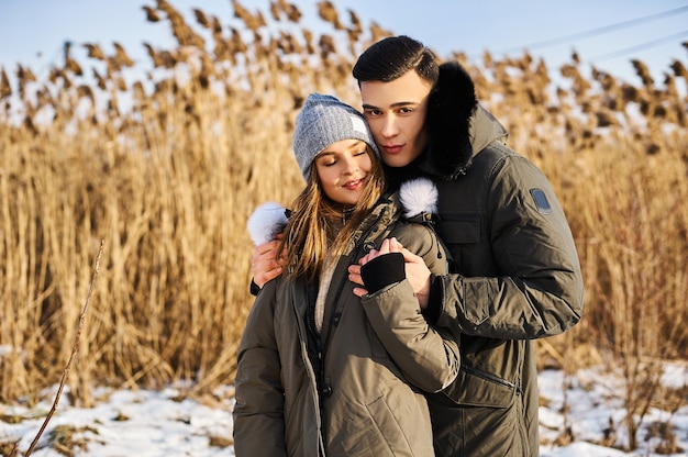 Gelukkige paar knuffelen en lachen buiten in de winter. foto dampreclame winterkleding