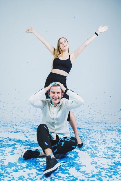 Gelukkige paar lachen om genderfeest terwijl ze in blauwe confetti zitten Genderfeest