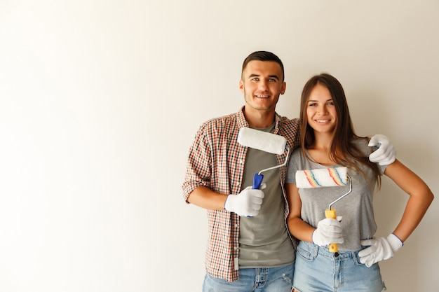 Gelukkige paar omarmen na renovatie hun nieuwe huis samen met verfroller