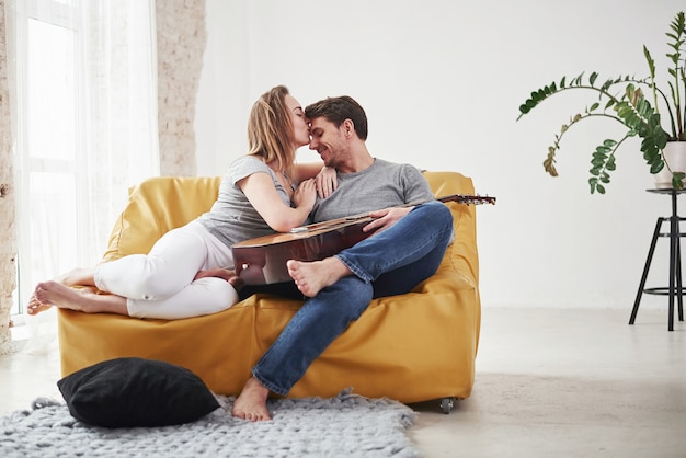 Gelukkige paar ontspannen op de gele bank in de woonkamer van hun nieuwe huis.