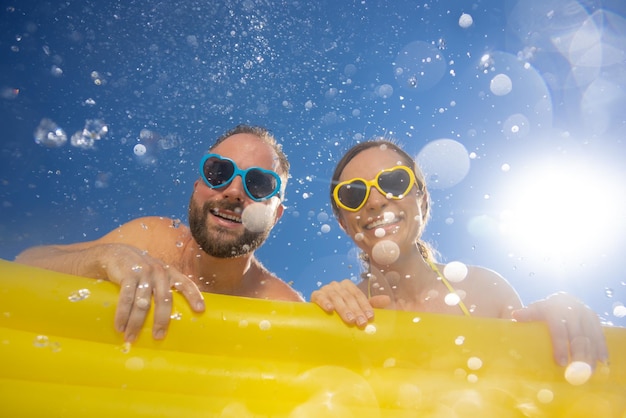 Gelukkige paar plezier op zomervakantie Mensen springen in het zwembad tegen de blauwe hemelachtergrond Actief vakantieconcept Voorjaarsvakantie