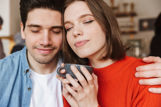 Gelukkige paar vrouw en man plezier met gesloten ogen, terwijl ze rusten in restaurant en samen koffie of thee drinken