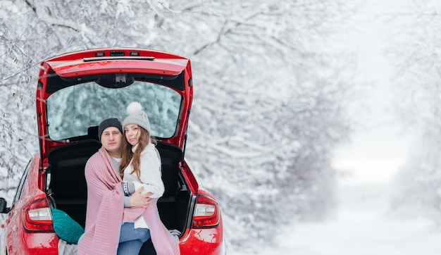 Gelukkige paar zitten in open auto terug, met stop. Romantisch reizend concept. Winter bos.