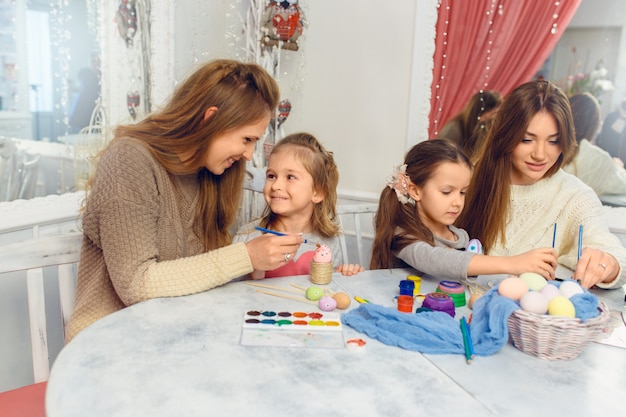 Gelukkige pasen-familie die kleurrijke paaseieren thuis schilderen