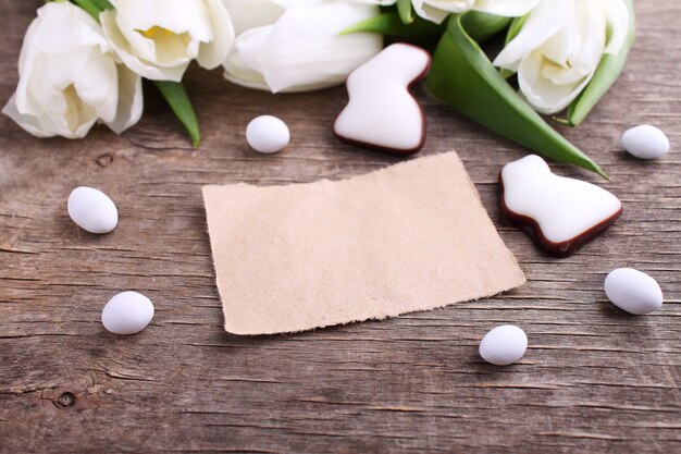 Gelukkige Pasen-groetkaart met witte tulpen en chocoladeeieren en konijntje, rustieke achtergrond.