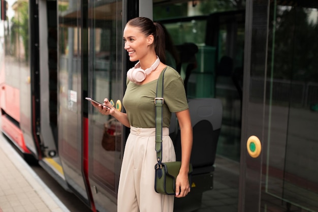 Gelukkige passagiersvrouw die telefoon gebruikt terwijl ze uit de tram stapt