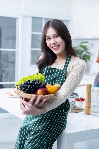 Gelukkige portret van jonge aziatische vrouw met een mandje met groenten van staan een vrolijke bereiden van eten en genieten van koken koken met groenten terwijl staan op een keuken condo leven of thuis