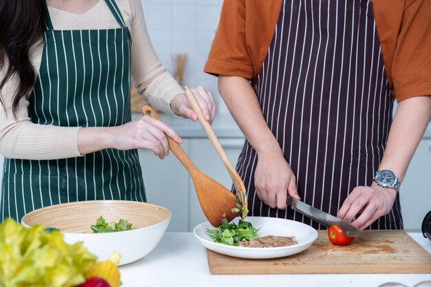 Gelukkige portret van liefhebbende jonge aziatische van plezier staan een vrolijke bereiden van eten en genieten koken koken met groenten vlees brood terwijl staan op een keuken condo leven of thuis