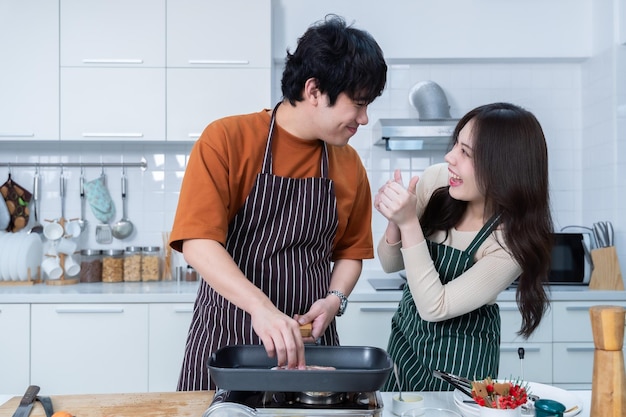 Gelukkige portret van liefhebbende jonge aziatische van plezier staan een vrolijke bereiden van eten en genieten koken koken met groenten vlees brood terwijl staan op een keuken condo leven of thuis