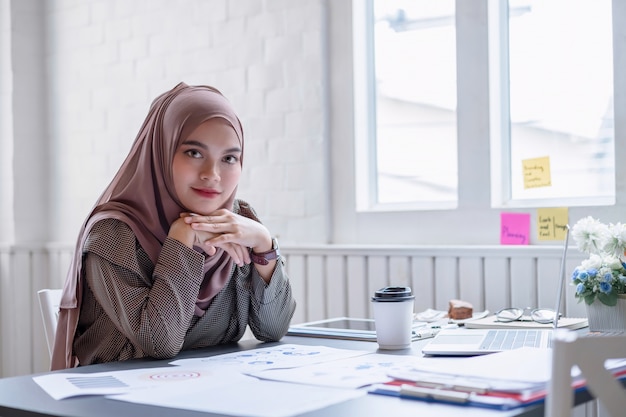 Gelukkige professionele Arabische onderneemster bruine hijab die thuis werkt.