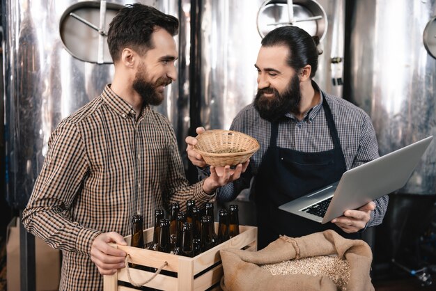 Gelukkige professionele brouwers die de mout inspecteren.