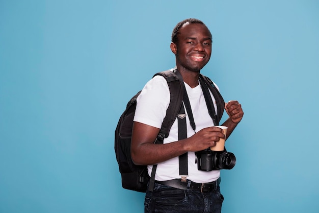 Gelukkige professionele fotograaf met rugzak en camera klaar voor vakantiereis. Fotografieliefhebber die op stedentrip gaat terwijl hij een reistas en DSLR-camera heeft.