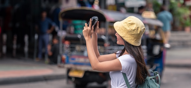 Foto gelukkige reizigers aziatische vrouw op straatmarkt met camera, in de stad van bangkok van thailand.