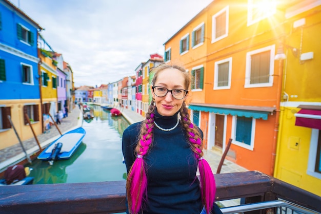 Gelukkige reizigersvrouw die plezier heeft in de buurt van kleurrijke huizen op het burano-eiland in de venetiaanse lagune en