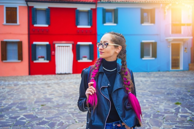 Gelukkige reizigersvrouw die plezier heeft in de buurt van kleurrijke huizen op het burano-eiland in de Venetiaanse lagune en